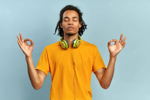 Homem afro-americano calmo meditação relaxante, nenhum alívio livre de estresse no conceito de trabalho, empresário tranquilo consciente ou estudante praticando exercícios de ioga respiração em roupa casual, parede azul isolada . — Fotografia de Stock