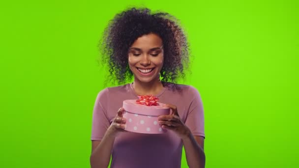 Sorrindo bela américa africana jovem abre uma caixa de presente — Vídeo de Stock