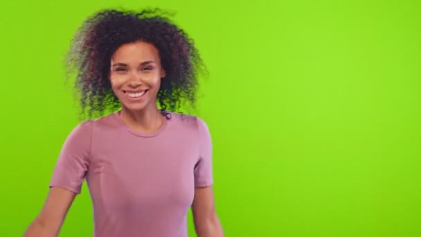 Linda joven afroamericana sonriente mujer gira y coquetea en la pantalla verde — Vídeos de Stock