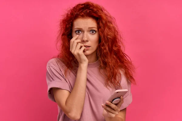 Assustado jovem irritado vermelho cabelo caucasiano menina segurando smartphone — Fotografia de Stock