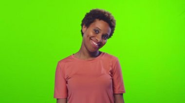 Çekici genç Afrikalı Amerikalı kadın göz kırpıyor ve başparmağını kroma anahtarında gösteriyor.