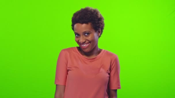 Agradable mujer afroamericana de pelo corto tiene expresión tímida en la pantalla verde — Vídeo de stock
