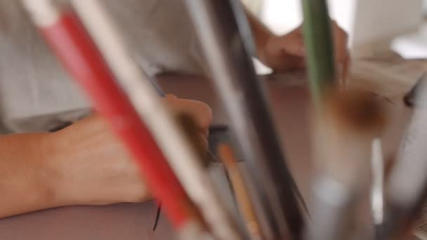 Gros plan main de femme artiste tient un pinceau, dessiner un satellite de la terre avec de l'huile