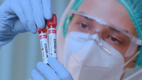 Le docteur portant la combinaison protectrice tient le tube à essai avec l'échantillon de sang Covid-19 — Video