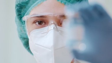 Kadın doktor elinde COVID-19 yeni koronavirüs aşısı şişesi tutuyor.