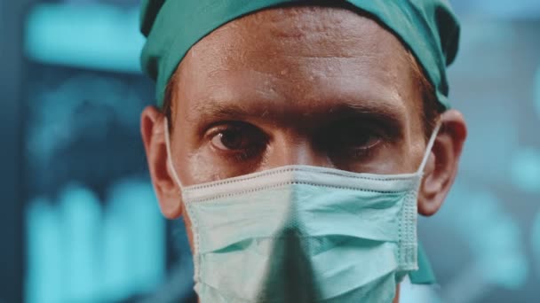 Retrato de um médico cansado usando um boné cirúrgico e uma máscara protetora — Vídeo de Stock
