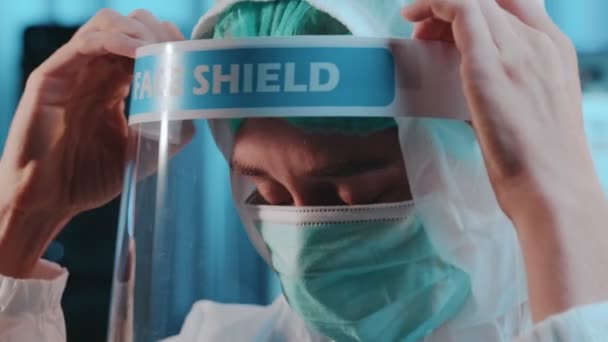 Ritratto di infermiera donna togliere lo scudo facciale dopo il turno in ospedale guardando la macchina fotografica — Video Stock