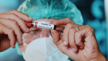 Laboratuvar çalışanı Coronavirus testi için test tüpünü kanla inceliyor.