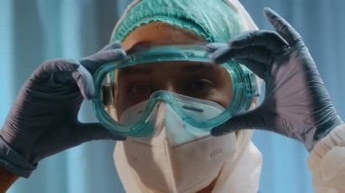 Kişisel koruyucu giysi giyen ve gözlük takan kadın doktor.