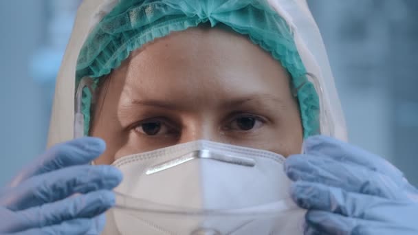 Ung kvinna läkare i hazmat kostym sätter på medicinska glasögon och skyddsmask — Stockvideo