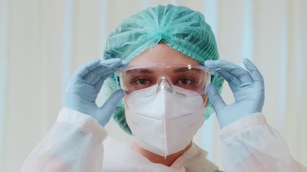 Donna operaia medica con maschera protettiva KN95 toglie gli occhiali medici — Video Stock