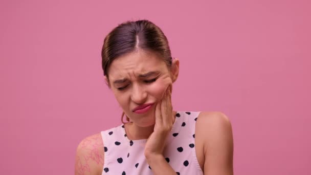 Žena trpí těžkou bolestí zubů na růžové zdi pozadí. — Stock video