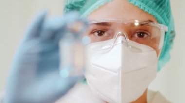 Kadın doktor elinde bir ampul koronavirüs aşısı tutuyor..