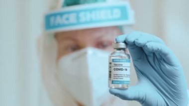 Doktor, CORONAVIRUS 'a karşı aşı ile korunan bir ampul tutuyor..