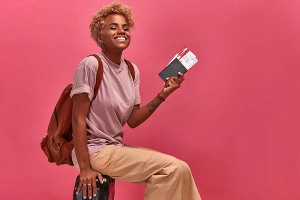 Zwarte vrouw toerist met rugzak houdt paspoort en tickets in haar handen — Stockfoto