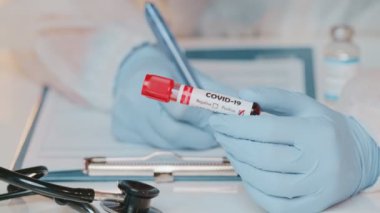 COVID-19 pozitif kan testiyle doktorların ellerindeki tüpü kapatın.