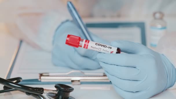 Close-up van de handbuis van de arts met positieve bloedtest op COVID-19 — Stockvideo
