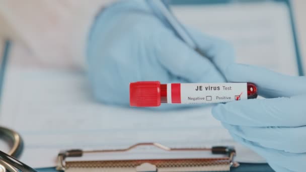 Le médecin tient une éprouvette sanguine positive pour le virus JE — Video