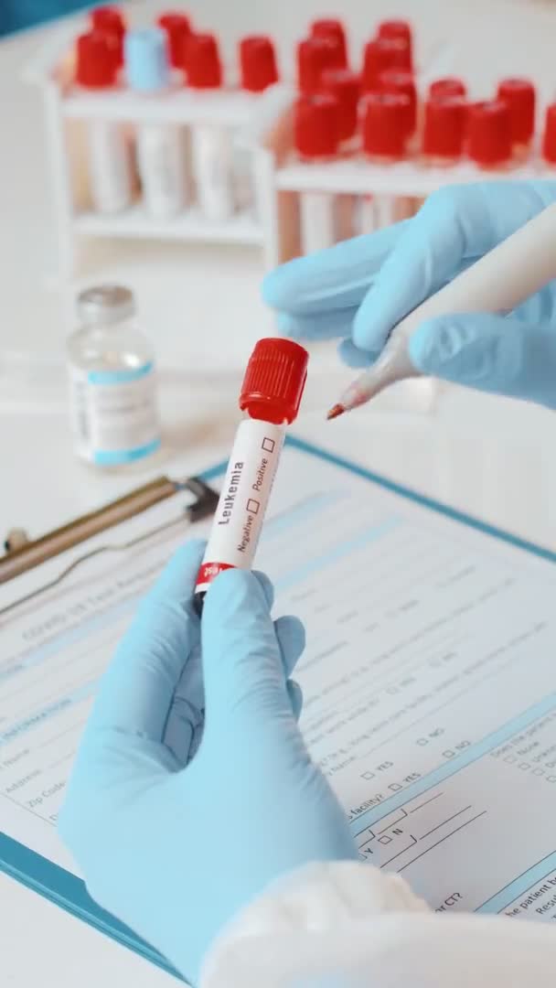 Imagens verticais do médico detém tubo de amostra de sangue da mão para teste de células de leucemia — Vídeo de Stock