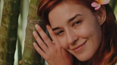 Genç kızıl saçlı kadın bambu ormanında poz veriyor.