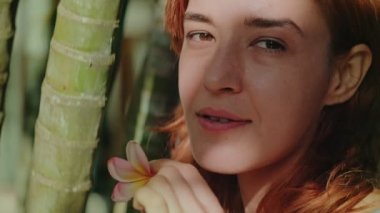 Genç kızıl saçlı kadın bambu ormanında poz veriyor.