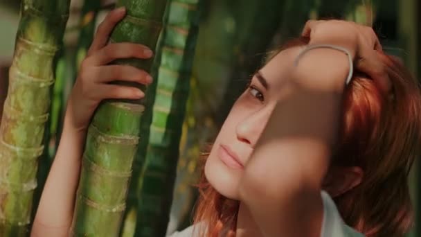 Молодая рыжая женщина позирует в бамбуковом лесу — стоковое видео