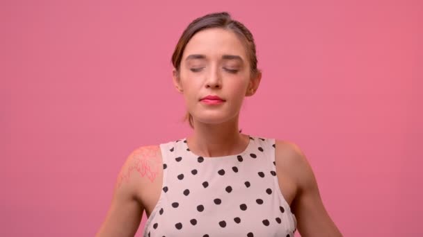 Calm caucasian woman relaxes meditating on pink background in studio. — Stock Video