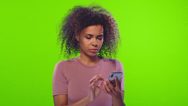 Nervózní Afroameričanka používá mobilní telefon na zelené — Stock video