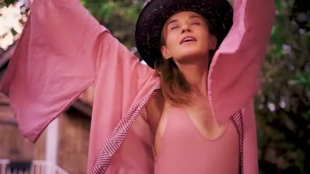 Młoda ruda kobieta w różowym kimono wiruje w tańcu w tropikalnym raju — Wideo stockowe