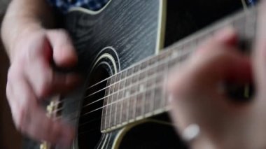Mavi Kareli gömlekli bir adam bir yakın çekim gitar çalıyor