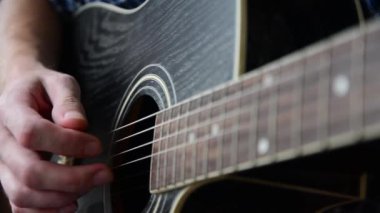 Mavi Kareli gömlekli bir adam bir yakın çekim gitar çalıyor