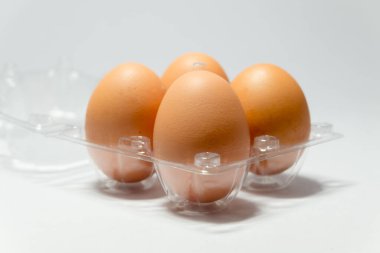 Beyaz arka planda plastik ambalajlı taze tavuk yumurtası.