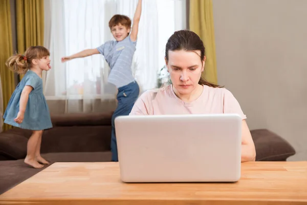 Home office. Working from home vs. Mom e Works with two kids on the Internet on a laptop at home. quarantine. Corona Virus.