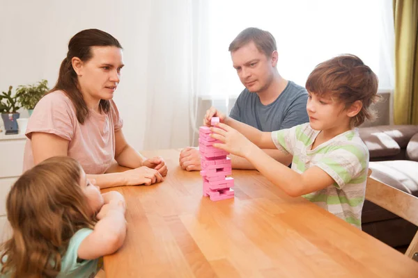 Happy family mom, dad and two kids playing board games at home. quarantine. Corona Virus. Family having fun playing at home. stay home concept