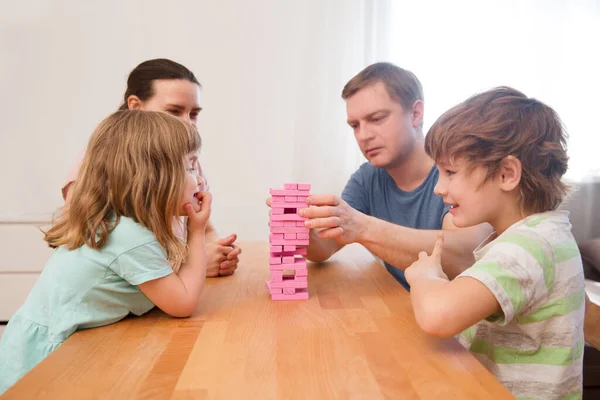 Happy family mom, dad and two kids playing board games at home. quarantine. Corona Virus. Family having fun playing at home. stay home concept