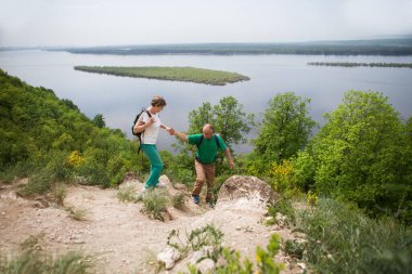 Sırt çantalı yaşlı çift dağları geziyor. Doğada yürüyen yaşlı bir çift. Karantina sona erdi. Konaklamalar, hiper-yerel seyahat, aile gezisi, kaçış, doğal çevre