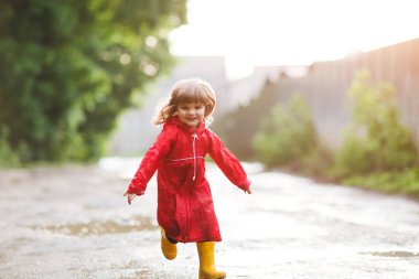 Yazın açık havada yağmurun ardından havuz başında oynayan mutlu çocuk da koşuyor.
