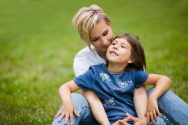 Anne ve küçük kızı dışarıda birlikte gülüp oynuyorlar.