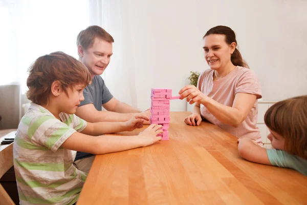 Happy family mom, dad and two kids playing board games at home. quarantine. Corona Virus. Family having fun playing at home. stay home concept