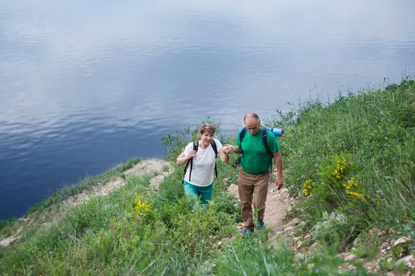 バックパック付きの高齢者のカップルは山を巡る シニアカップル自然の中で歩く — ストック写真