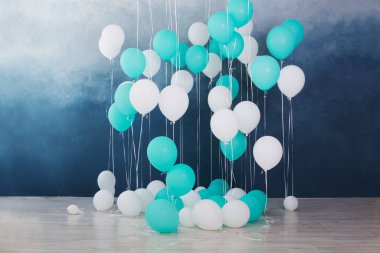 Koyu mavi duvar arka planında balonlar. Odadaki renkli balonlar doğum günü partisi için hazırlanıyor..