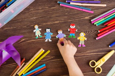 Çocuk kağıt işleriyle uğraşıyor. Tahta arka planda kağıt insanlar. Yaratıcı çocuk zanaatla oynuyor