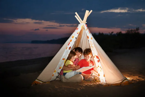 Mom Two Children Reading Book Flashlights Tent Evening River Bank — Stock Photo, Image