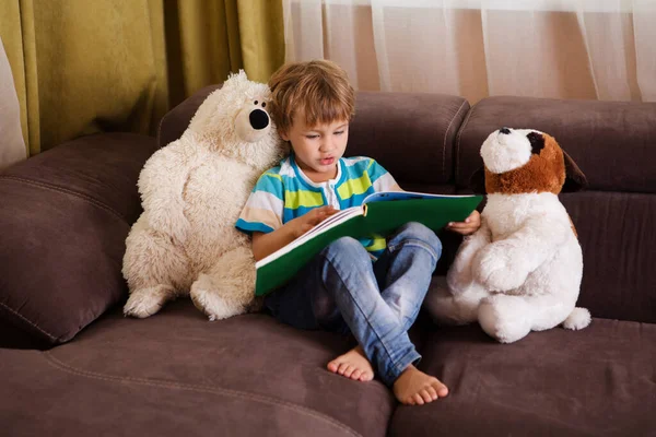 Netter Kleiner Junge Liest Buch Mit Plüschtieren Sitzt Auf Einem — Stockfoto
