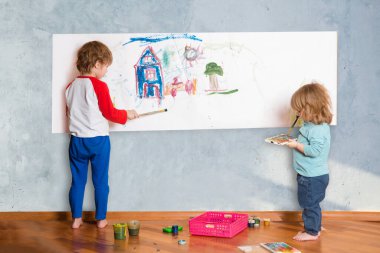 Odada duvarlara resim yapan iki küçük şirin çocuk.