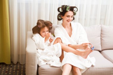 Saçlarında bigudiler olan anne ve kız evde manikür ve pedikür yapıyorlar. Saçlarında bigudiler var. Birlikte güzel vakit geçiriyoruz. Chelter yerinde. ev konsepti