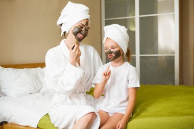 Anne ve kızı evde kilden maske yapıyorlar. Saçları beyaz bir banyo havlusuna sarılı. Birlikte güzel vakit geçiriyoruz. Chelter yerinde.. 