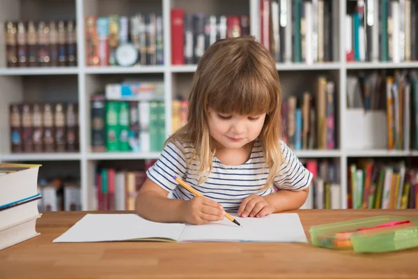 child do lessons at home.  kid study at home.  quarantine. Corona Virus. schoolgirl  study online at home. homeschooling, distant learning. schoolkid drawing at the desk with a bookcase against the background of