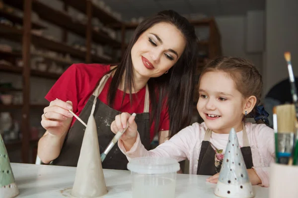 Çömlekçilik atölyesinde annesiyle birlikte çömlek boyayan çocuk.
