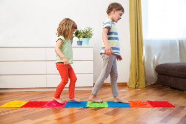 Prematüre çocukların iki çocuğu evde masaj minderinde yürüyor. Düz taban ve hallux valgus önleme.